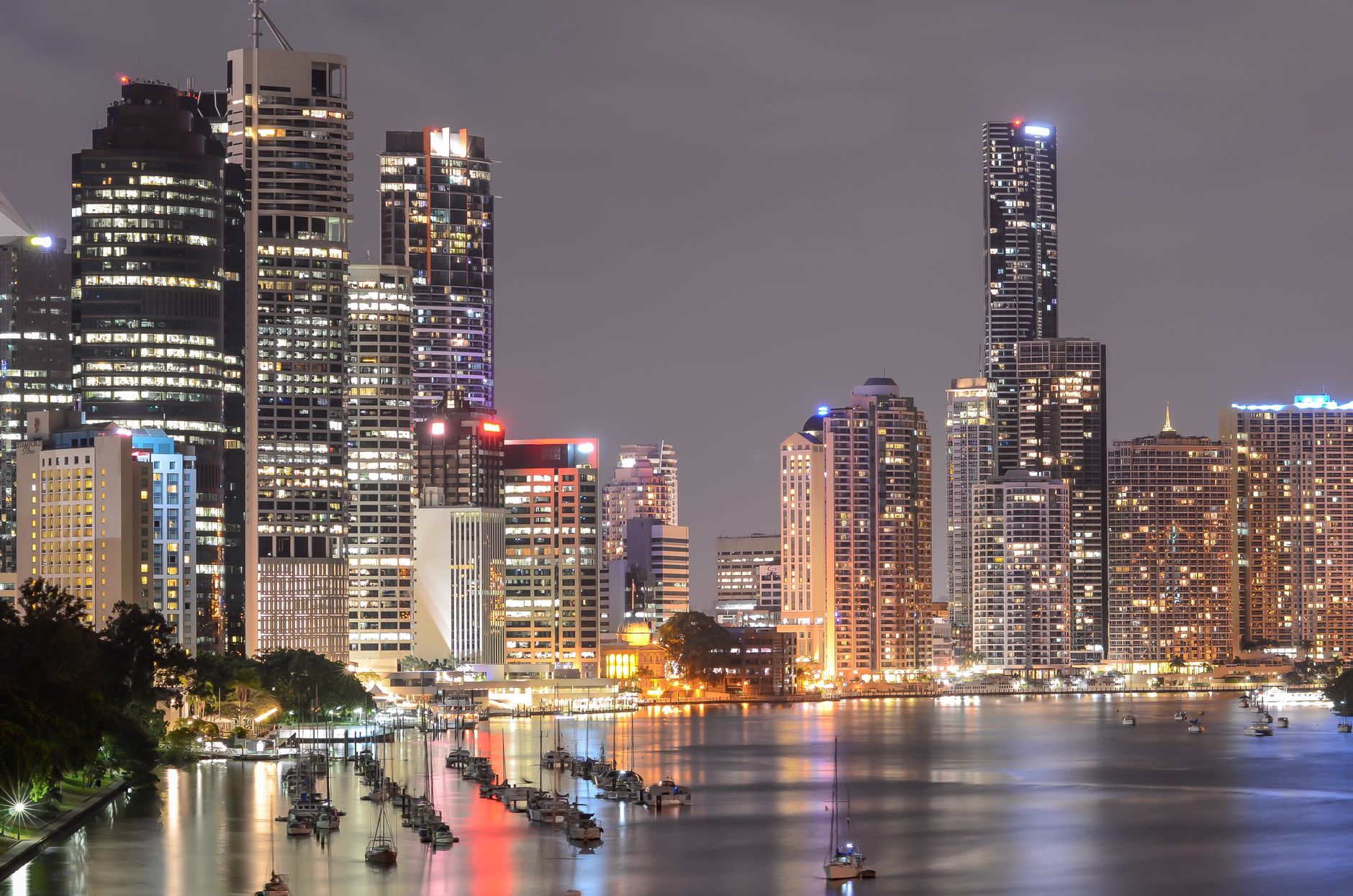Brisbane's illuminated skyline and riverfront marina at night, reflecting Queensland's booming property market.