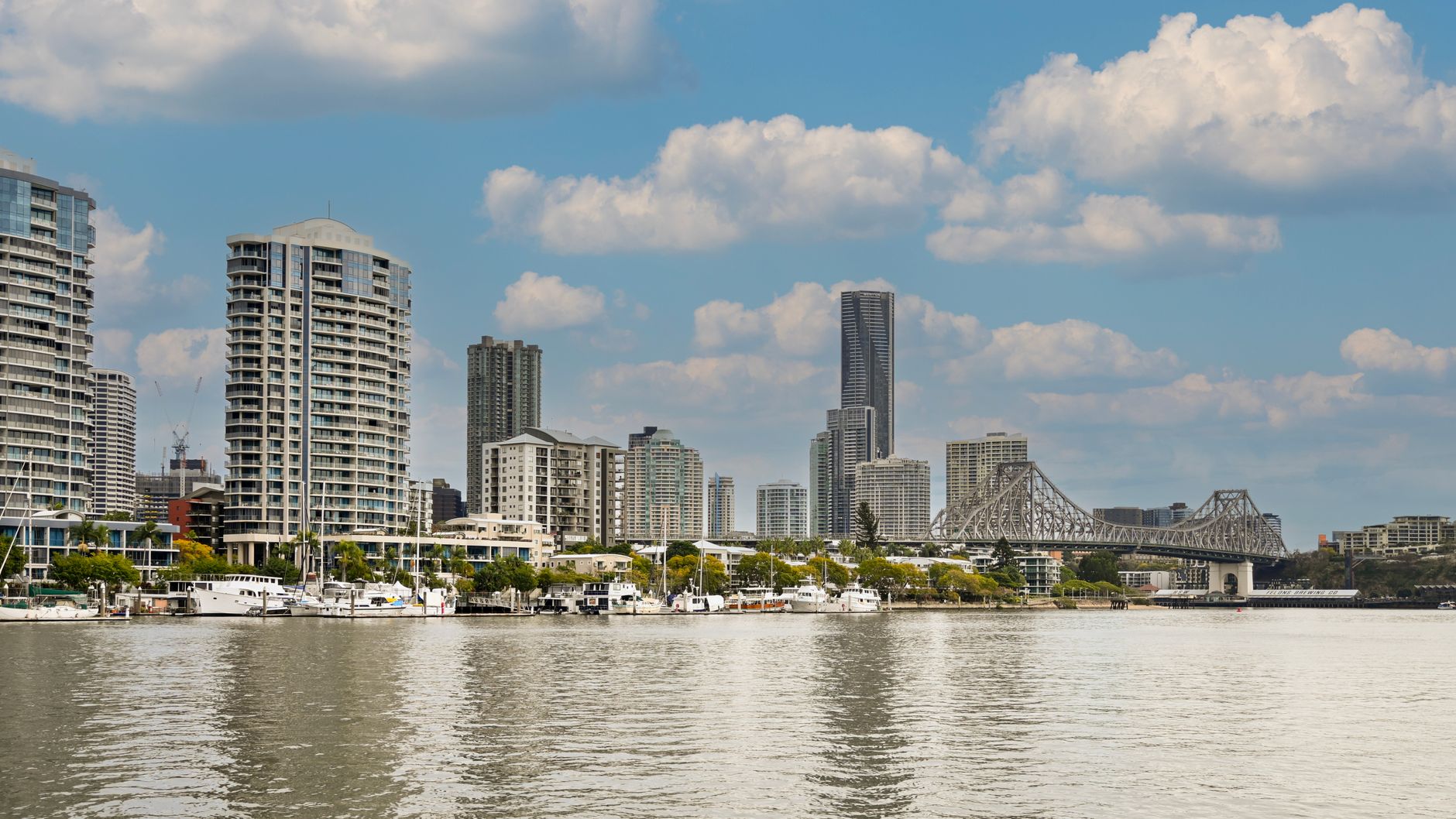A vibrant view of Brisbane's skyline featuring the Story Bridge over the river in a bright daytime setting.